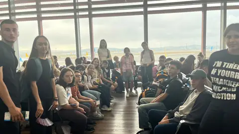 Uçuş kapısında oturup bekleyen öğrenciler