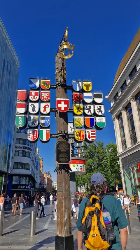 Leicester Square'de bayraklı direğin yanında öğrenciler