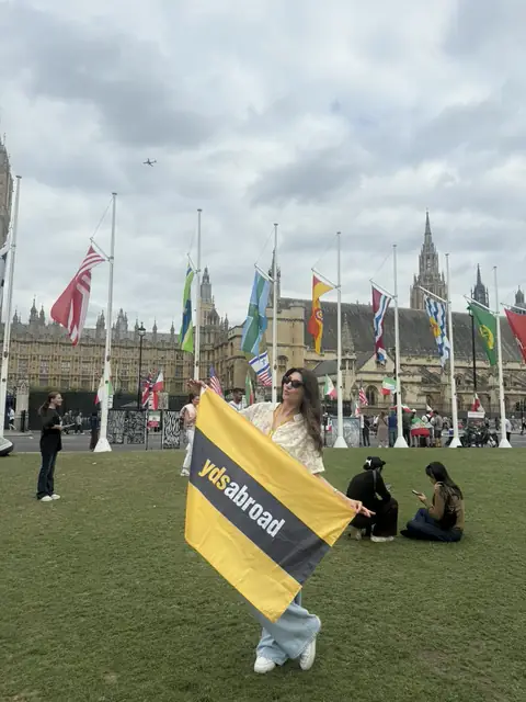 Parlamento Meydanı'nda YDS Abroad bayrağı tutan bir genç