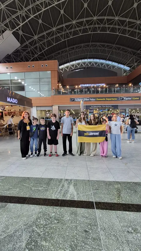 Tren istasyonunda pankartla poz veren grup