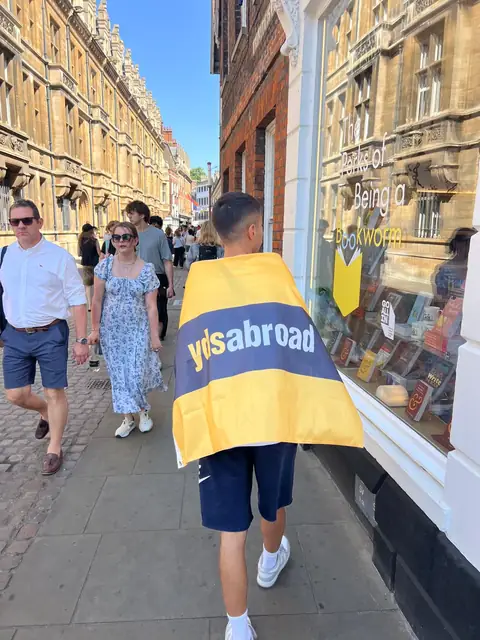 Oxford sokağında pankartı omzuna almış yürüyen öğrenci