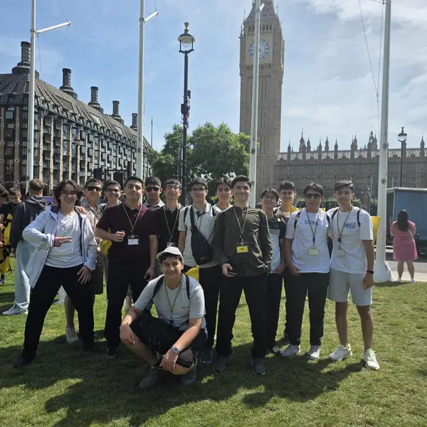 Big Ben önünde çimenlikte poz veren öğrenciler